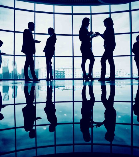 Several colleagues communicating in office against window